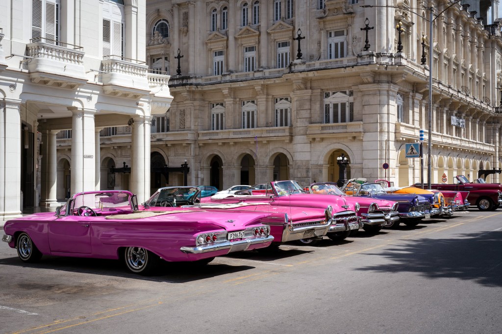 Colorful classic cars lined up along a city street. La Habana, Cuba.