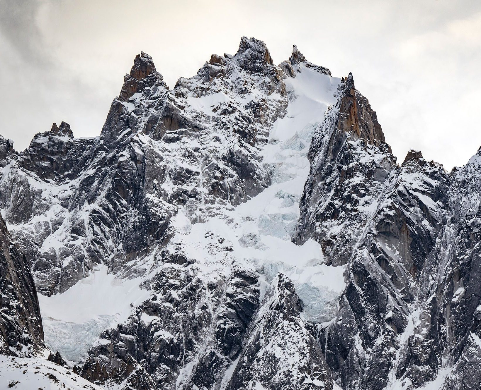 Snow-covered mountain rising above a dramatic landscape. Chamonix, France.