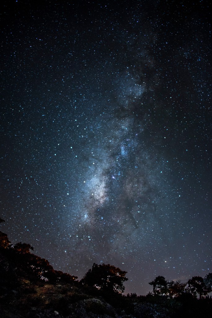 Milky Way stretching across a clear night sky above the landscape.