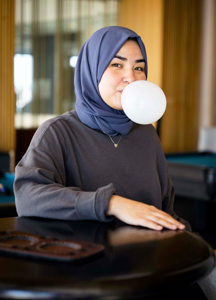 Portrait of a woman blowing a bubble against a neutral background.