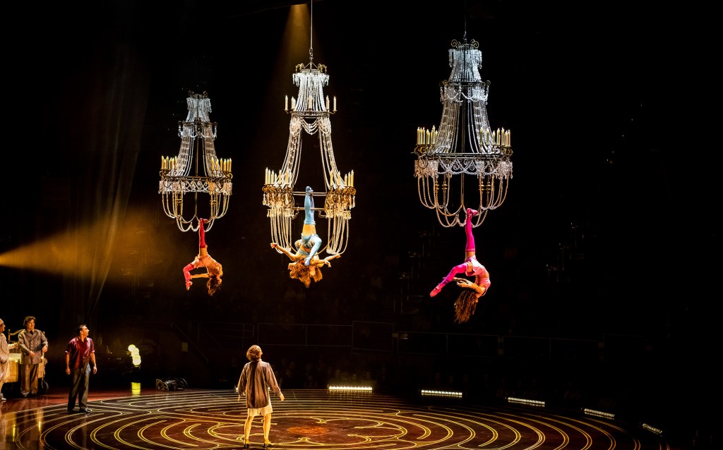 Aerial performers suspended above a theatrical stage during a live performance.
