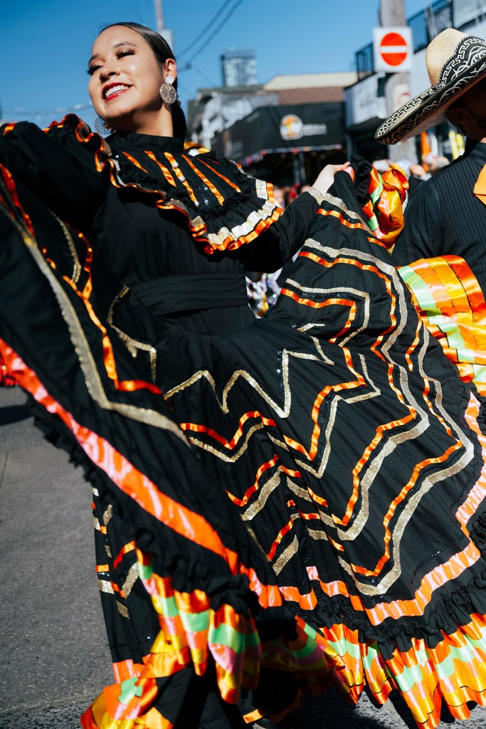 Mexican folk dancer performing outdoors in a colorful traditional dress.