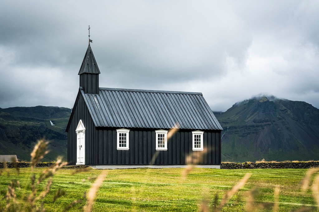 Black church surrounded by an open landscape in Iceland.