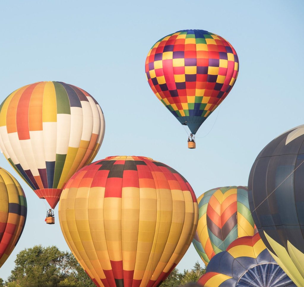Hot air balloons floating across the sky during a balloon festival.