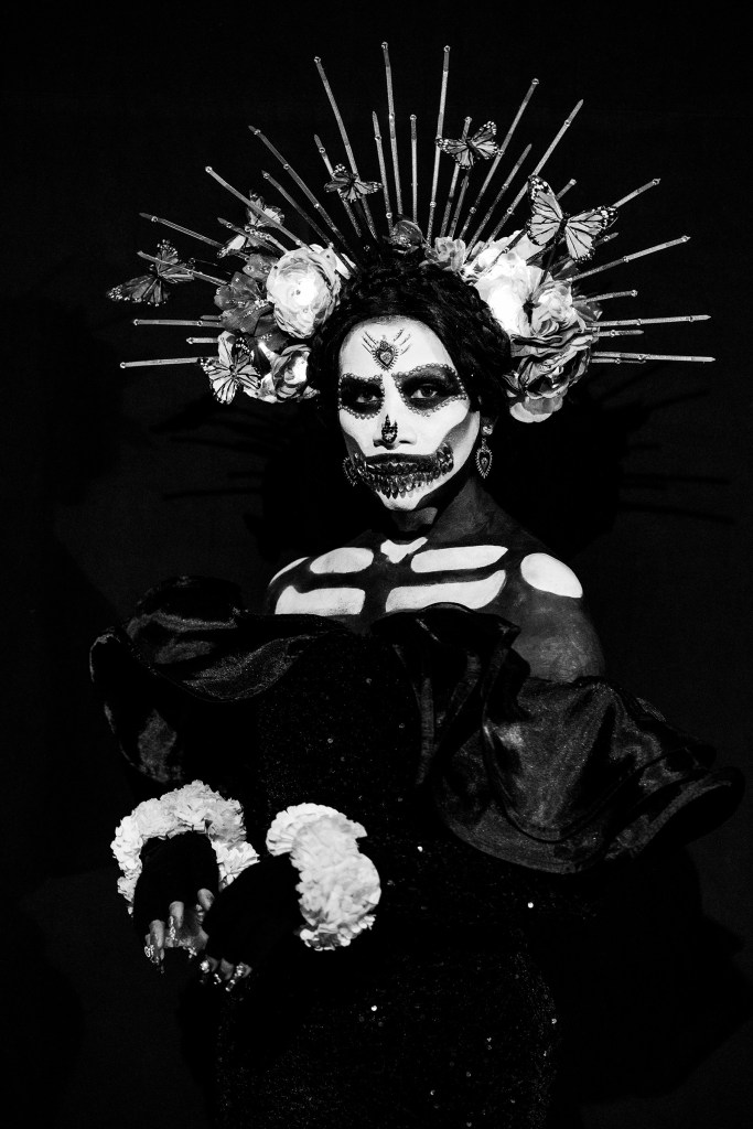 Black-and-white portrait of a performer wearing traditional Catrina makeup.