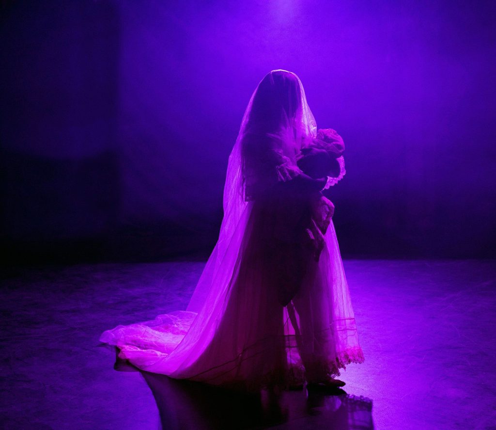 Performer silhouetted against dramatic purple stage lighting.